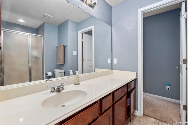 bathroom featuring vanity, an enclosed shower, a textured ceiling, and toilet