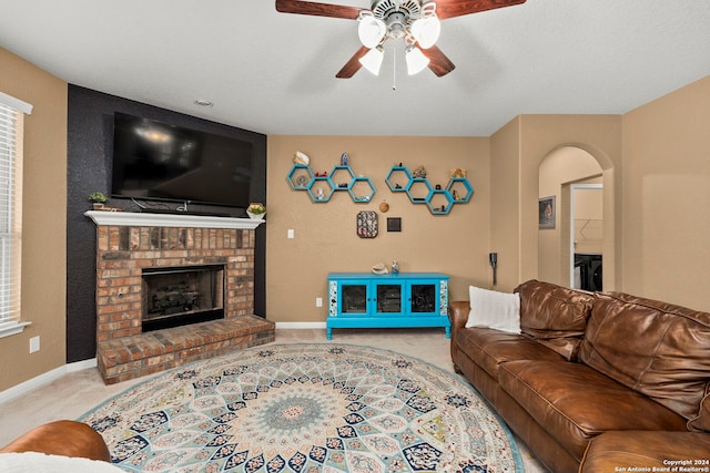 carpeted living room with a brick fireplace and ceiling fan