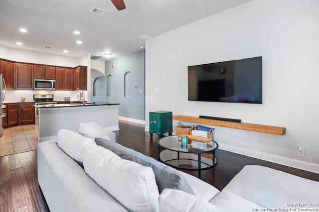 living room with light wood-type flooring, ceiling fan, and sink