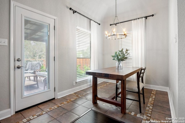 dining area with dark tile patterned floors and a chandelier