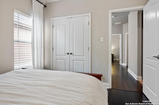 bedroom featuring dark hardwood / wood-style flooring, a closet, and multiple windows