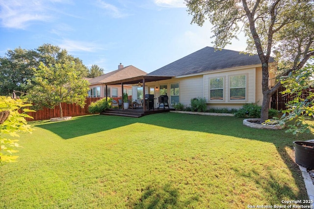 back of property with a deck and a lawn