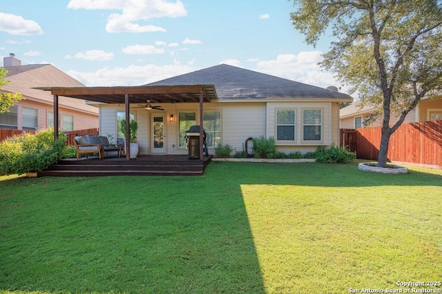 back of property with ceiling fan, a yard, and a wooden deck