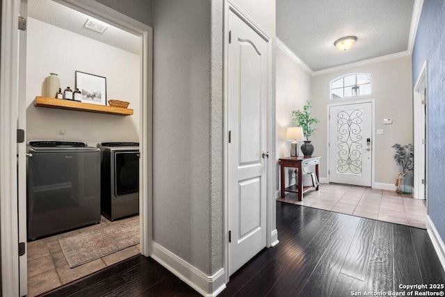 entryway featuring washer and dryer, ornamental molding, a textured ceiling, and hardwood / wood-style flooring