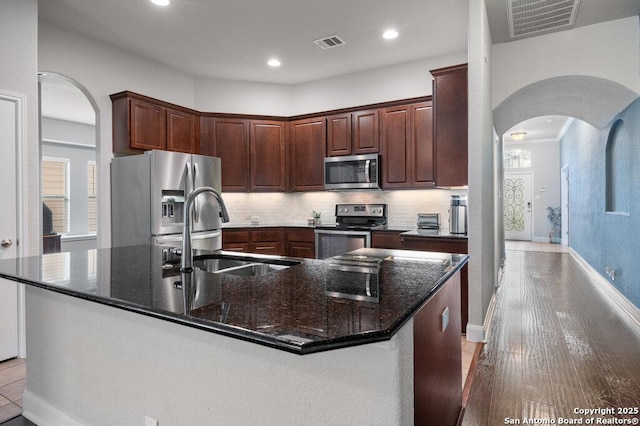 kitchen featuring tasteful backsplash, stainless steel appliances, an island with sink, and sink