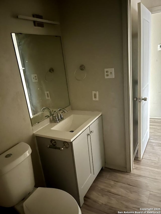 bathroom with vanity, toilet, and hardwood / wood-style floors