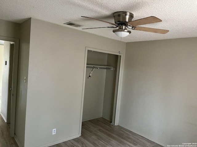 unfurnished bedroom with ceiling fan, a textured ceiling, light wood-type flooring, and a closet