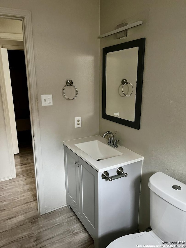 bathroom with vanity, toilet, and hardwood / wood-style floors