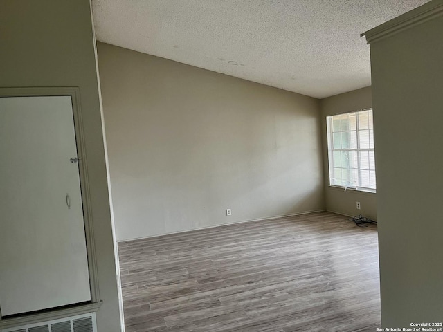 spare room featuring a textured ceiling and light wood-type flooring