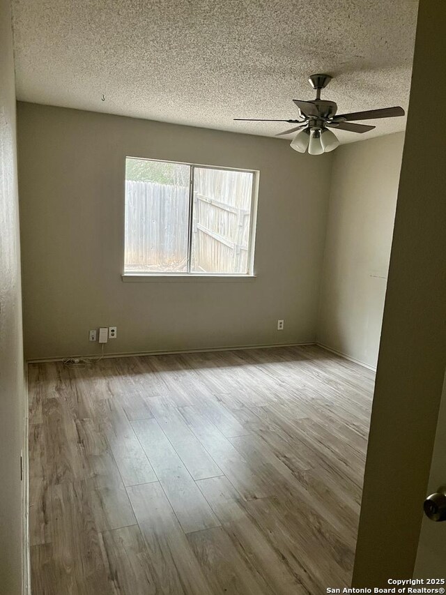 empty room featuring a textured ceiling, ceiling fan, and light hardwood / wood-style flooring