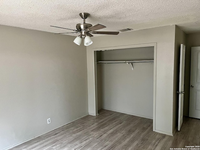 unfurnished bedroom featuring hardwood / wood-style flooring, ceiling fan, a closet, and a textured ceiling