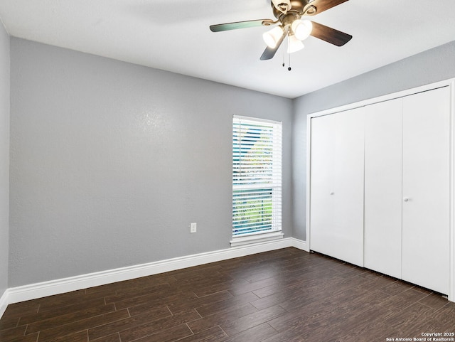 unfurnished bedroom featuring ceiling fan, a closet, and dark wood-type flooring