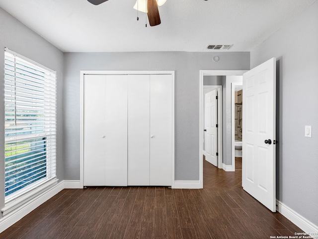 unfurnished bedroom with dark hardwood / wood-style flooring, ceiling fan, and a closet