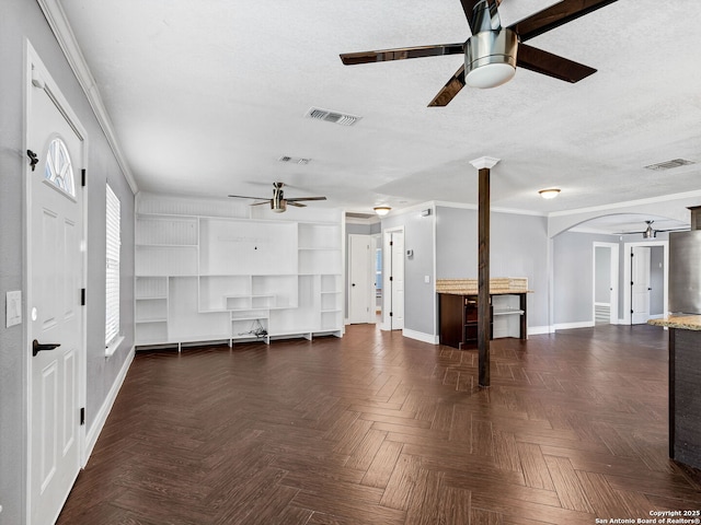 unfurnished living room featuring dark parquet flooring, a textured ceiling, ceiling fan, and ornamental molding