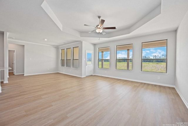 unfurnished living room featuring a raised ceiling, ceiling fan, and light hardwood / wood-style flooring