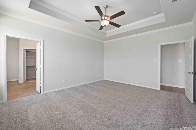 spare room with a raised ceiling, crown molding, carpet flooring, and ceiling fan