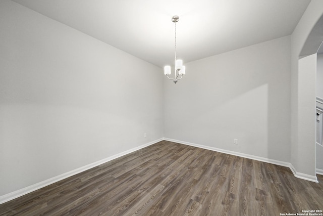 spare room with a notable chandelier and dark hardwood / wood-style floors