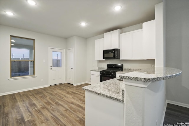 kitchen with kitchen peninsula, light stone countertops, dark wood-type flooring, black appliances, and white cabinets