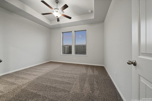 carpeted empty room featuring ceiling fan and a raised ceiling