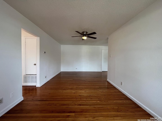 empty room with a textured ceiling, ceiling fan, and dark wood-type flooring