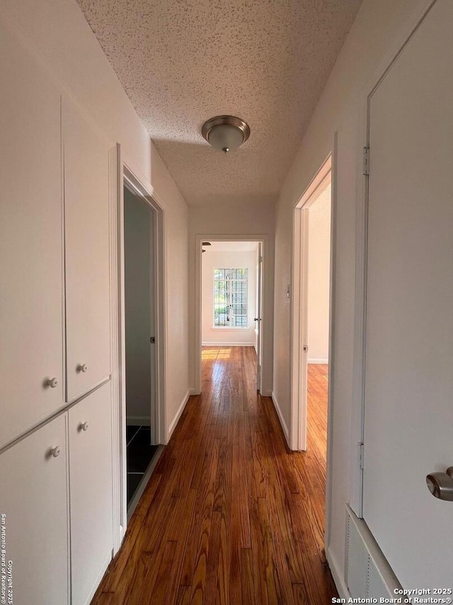 hallway with a textured ceiling and dark wood-type flooring