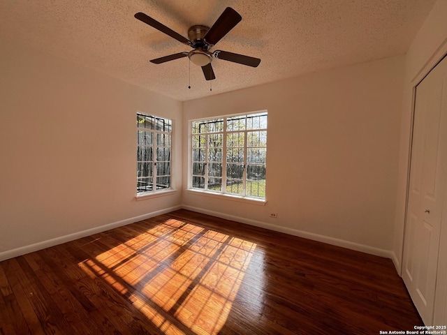 empty room featuring dark hardwood / wood-style floors, ceiling fan, and a textured ceiling