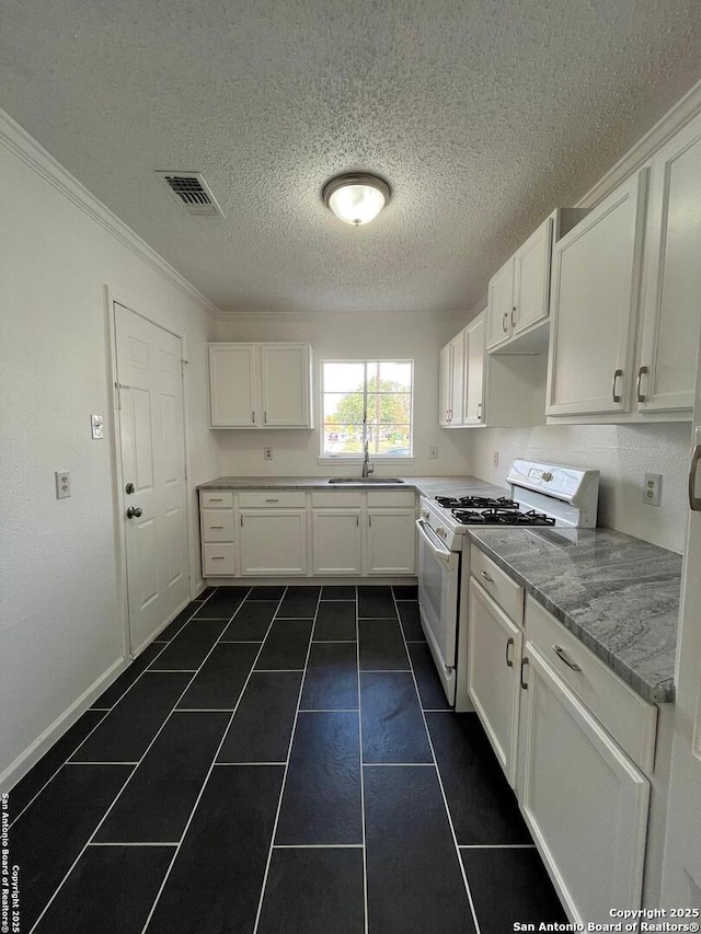 kitchen with white range with gas stovetop, crown molding, sink, light stone counters, and white cabinetry