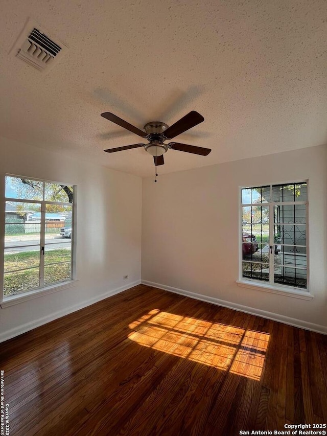 empty room featuring a textured ceiling, ceiling fan, and dark hardwood / wood-style floors