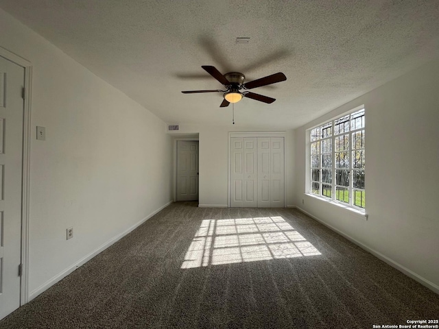 unfurnished bedroom with carpet flooring, ceiling fan, a closet, and a textured ceiling