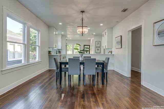 dining area featuring dark hardwood / wood-style floors, a wealth of natural light, and an inviting chandelier