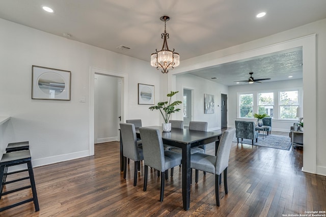 dining area featuring dark hardwood / wood-style flooring and ceiling fan with notable chandelier