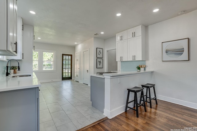 kitchen featuring sink, tasteful backsplash, kitchen peninsula, a breakfast bar area, and white cabinets