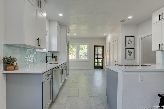 kitchen featuring kitchen peninsula, tasteful backsplash, sink, dishwasher, and white cabinets