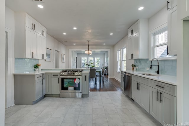 kitchen featuring pendant lighting, backsplash, sink, kitchen peninsula, and stainless steel appliances