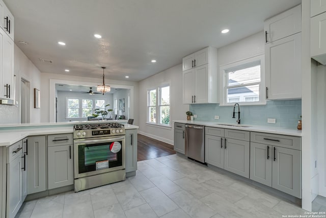 kitchen with ceiling fan, sink, tasteful backsplash, decorative light fixtures, and appliances with stainless steel finishes