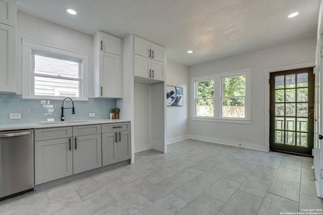 kitchen with backsplash, white cabinets, a textured ceiling, sink, and dishwasher