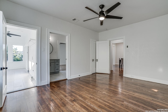 unfurnished bedroom featuring ensuite bathroom, dark hardwood / wood-style floors, and ceiling fan