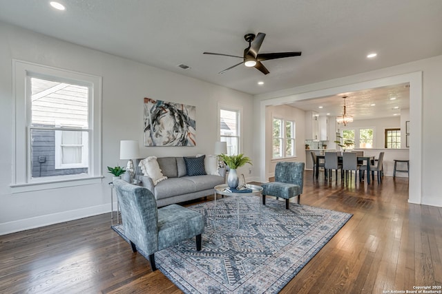 living room with ceiling fan with notable chandelier and dark wood-type flooring