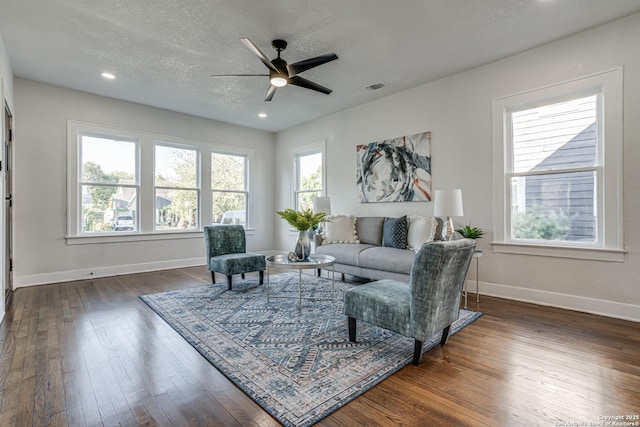 living room featuring a textured ceiling, ceiling fan, and dark wood-type flooring