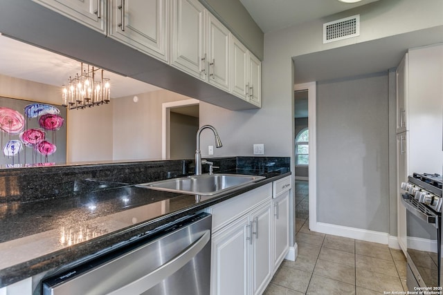 kitchen featuring white cabinetry, sink, dark stone counters, light tile patterned floors, and appliances with stainless steel finishes