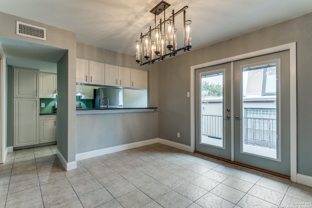 kitchen with stainless steel refrigerator, french doors, pendant lighting, and an inviting chandelier