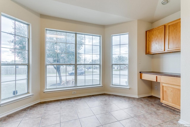 unfurnished dining area with built in desk and light tile patterned floors