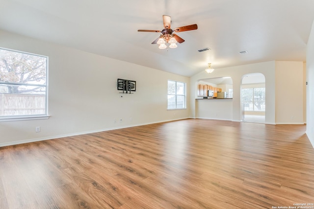 unfurnished living room with ceiling fan, a healthy amount of sunlight, light hardwood / wood-style floors, and lofted ceiling