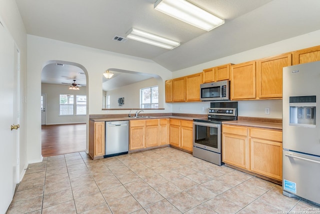 kitchen featuring ceiling fan, light tile patterned floors, stainless steel appliances, and lofted ceiling