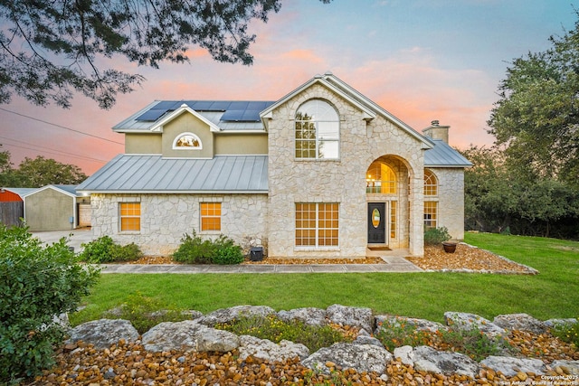 view of front of property with a lawn and solar panels