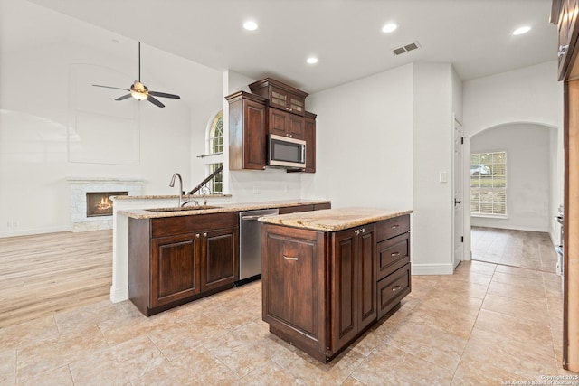 kitchen featuring ceiling fan, sink, dark brown cabinets, a kitchen island, and appliances with stainless steel finishes