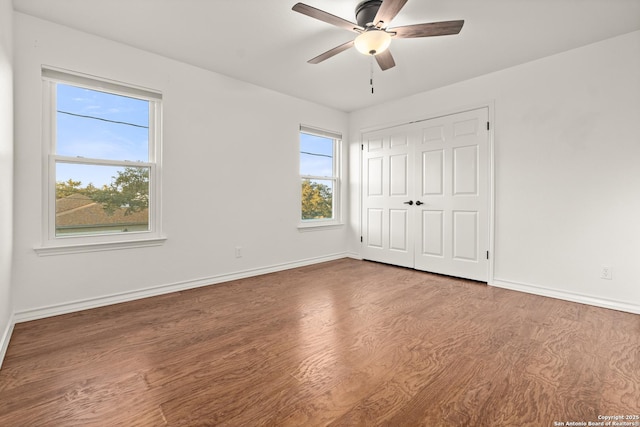 unfurnished bedroom with multiple windows, a closet, ceiling fan, and hardwood / wood-style flooring