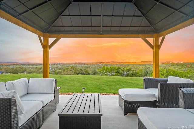 patio terrace at dusk with a gazebo, an outdoor living space, and a lawn