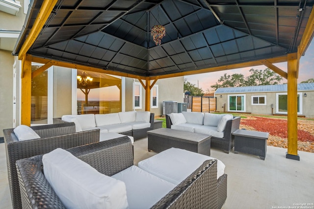 patio terrace at dusk with a gazebo, an outdoor hangout area, cooling unit, and an outdoor structure