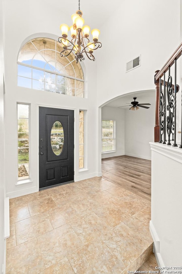 entryway with a high ceiling and ceiling fan with notable chandelier